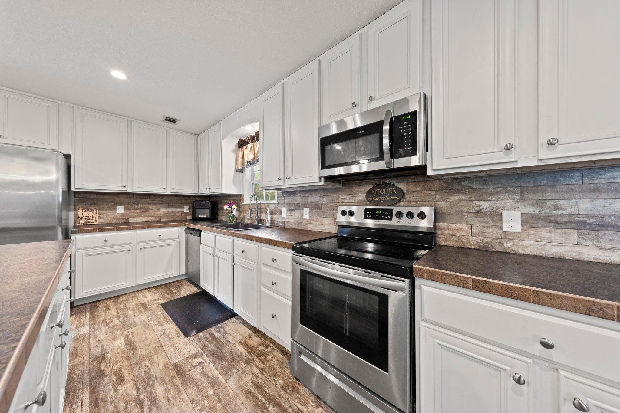 830 Squirrel Road DeFuniak Springs, FL 32433 - Photo 6 of 30 a kitchen with granite countertop white cabinets and stainless steel appliances