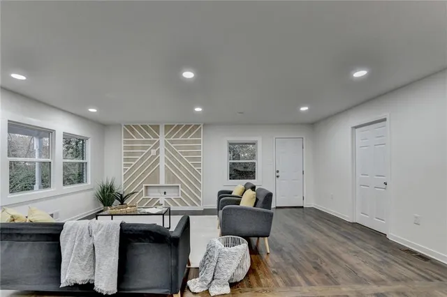 a living room with furniture a large window and wooden floor