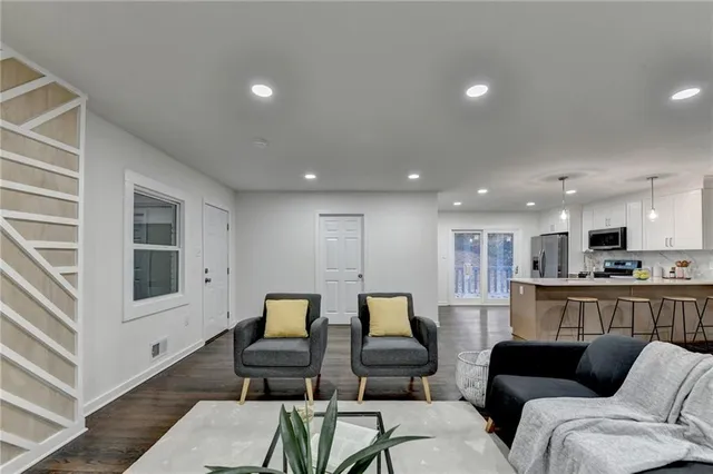 a living room with furniture and a view of kitchen