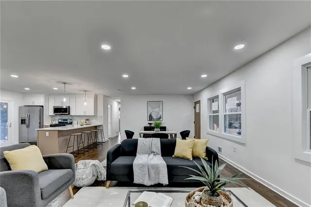 a living room with furniture kitchen view and a wooden floor