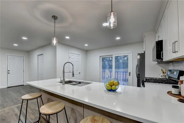 a kitchen with stainless steel appliances kitchen island granite countertop a sink a stove a microwave a counter space and cabinets