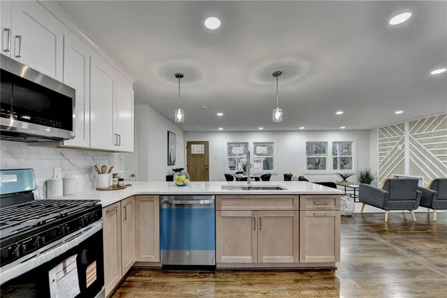 a kitchen with stainless steel appliances granite countertop a sink dishwasher stove top oven and cabinets with wooden floor