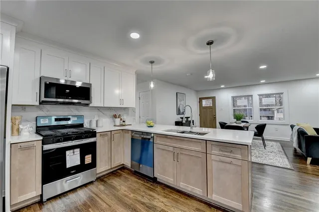 a kitchen with a sink a center island stainless steel appliances and cabinets