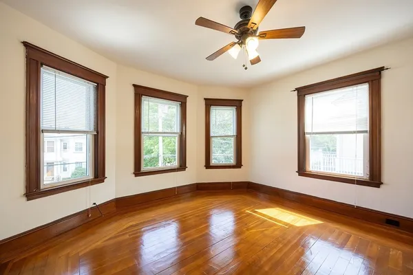 an empty room with wooden floor and windows
