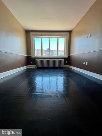 a view of an empty room with wooden floor and windows