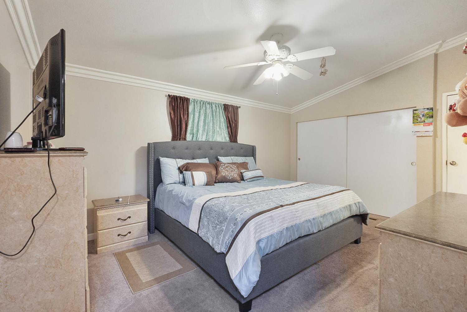 2841 Fowler Road, Unit 33 Ceres, CA 95307 - Photo 16 of 29 a bedroom with a large bed and a flat tv screen on dresser