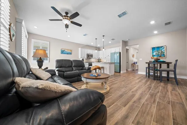 a kitchen with stainless steel appliances granite countertop a refrigerator a sink dishwasher a stove and white countertops with wooden floor