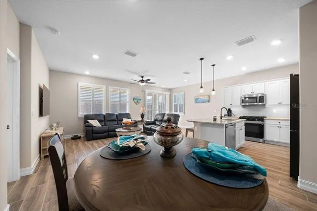 a kitchen with stainless steel appliances kitchen island granite countertop a refrigerator a stove a sink dishwasher and white cabinets with wooden floor