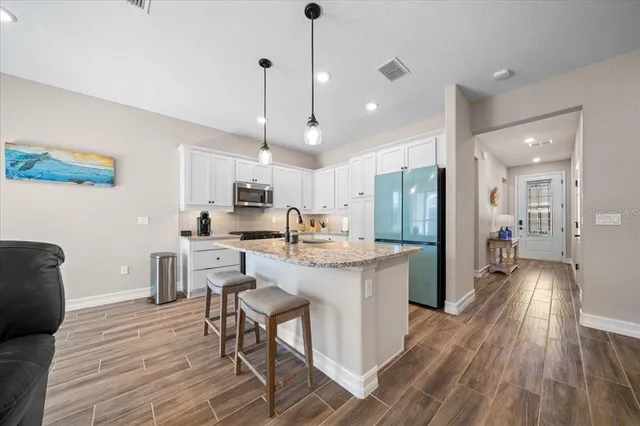 a kitchen with stainless steel appliances kitchen island granite countertop a stove a sink a dining table and chairs with wooden floor