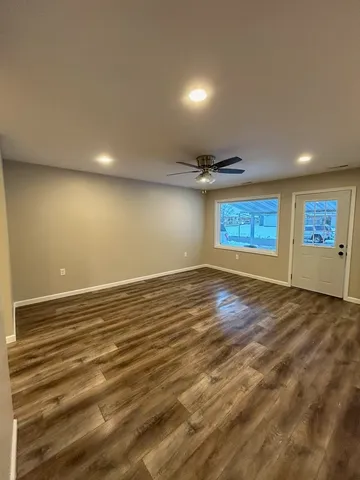 an empty room with wooden floor and windows