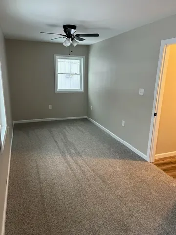 an empty room with windows and chandelier fan