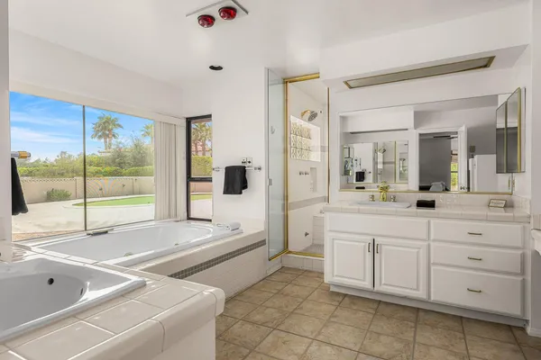 a spacious bathroom with a tub sink and mirror