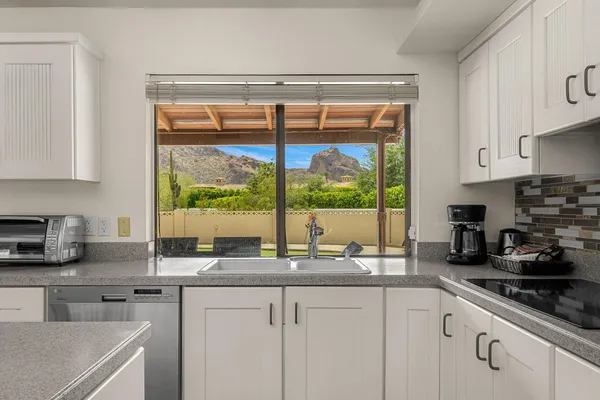 a kitchen with granite countertop a sink a counter top space cabinets and stainless steel appliances