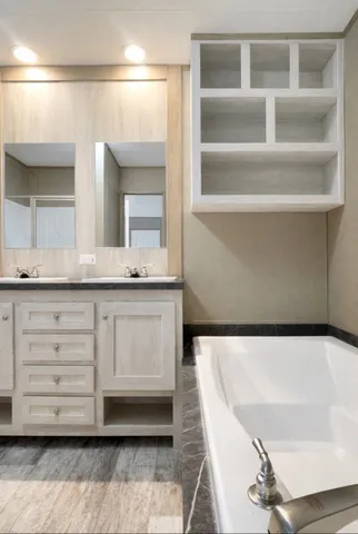 a bathroom with a tub a double vanity sink and a mirror