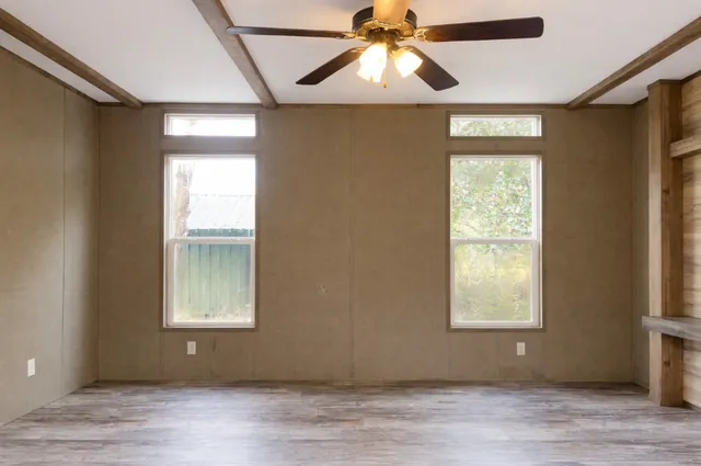 an empty room with wooden floor closet fan and windows