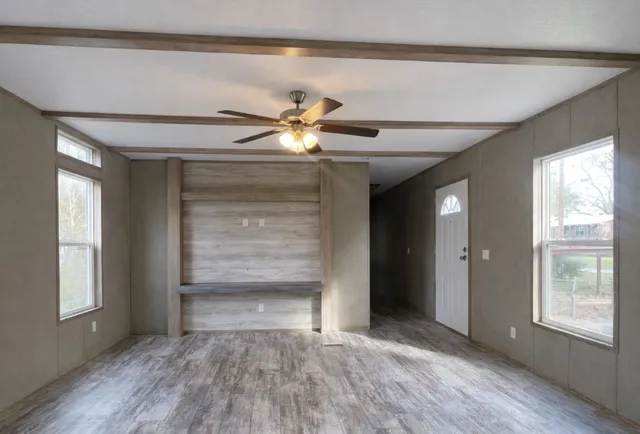 a view of an empty room with window and wooden floor