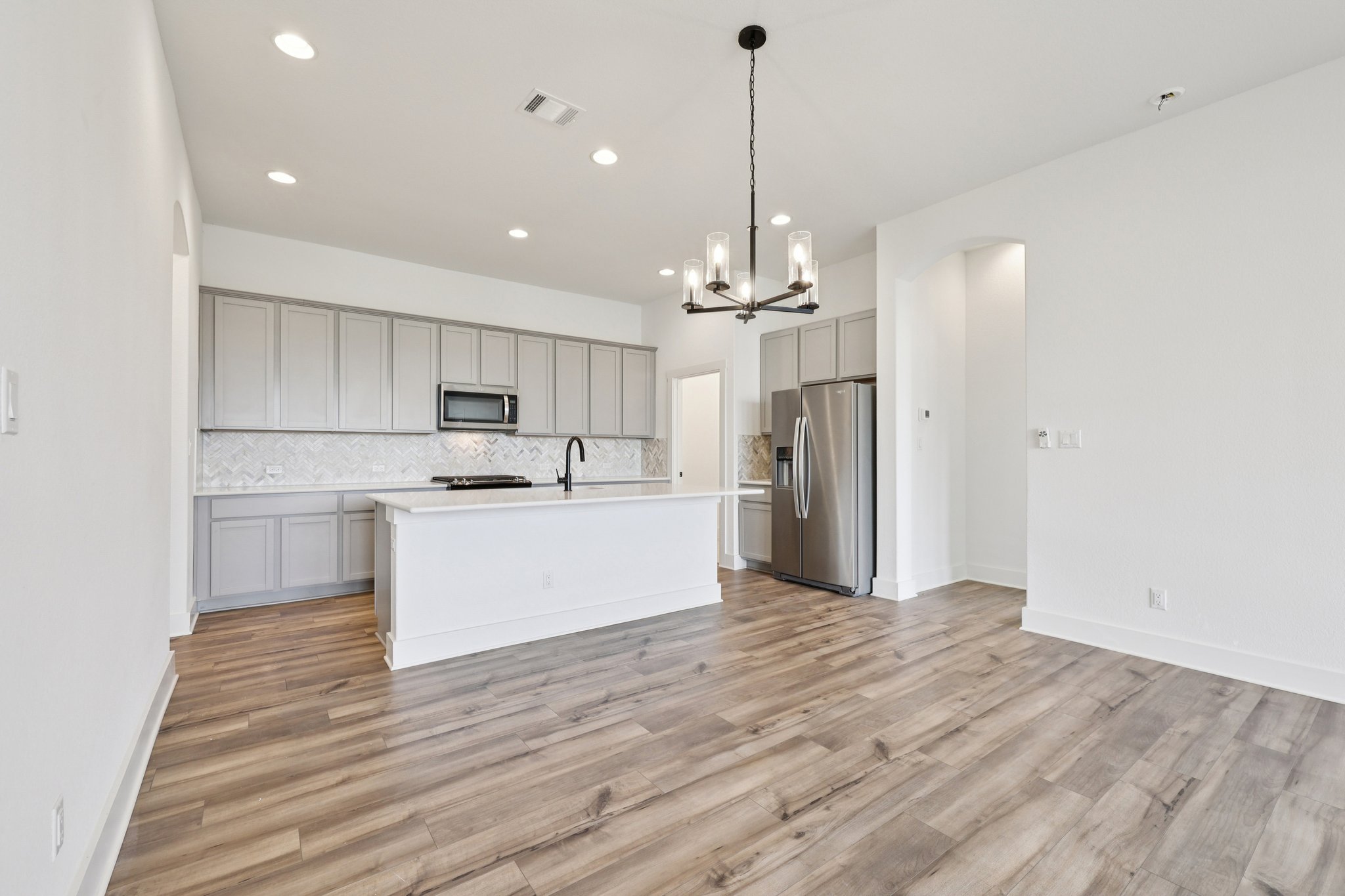8760 Wellspring Loop Hutto, TX 78634 - Photo 12 of 37 Kitchen with stainless steel appliances, gray cabinetry, a center island with sink, a chandelier, and decorative backsplash