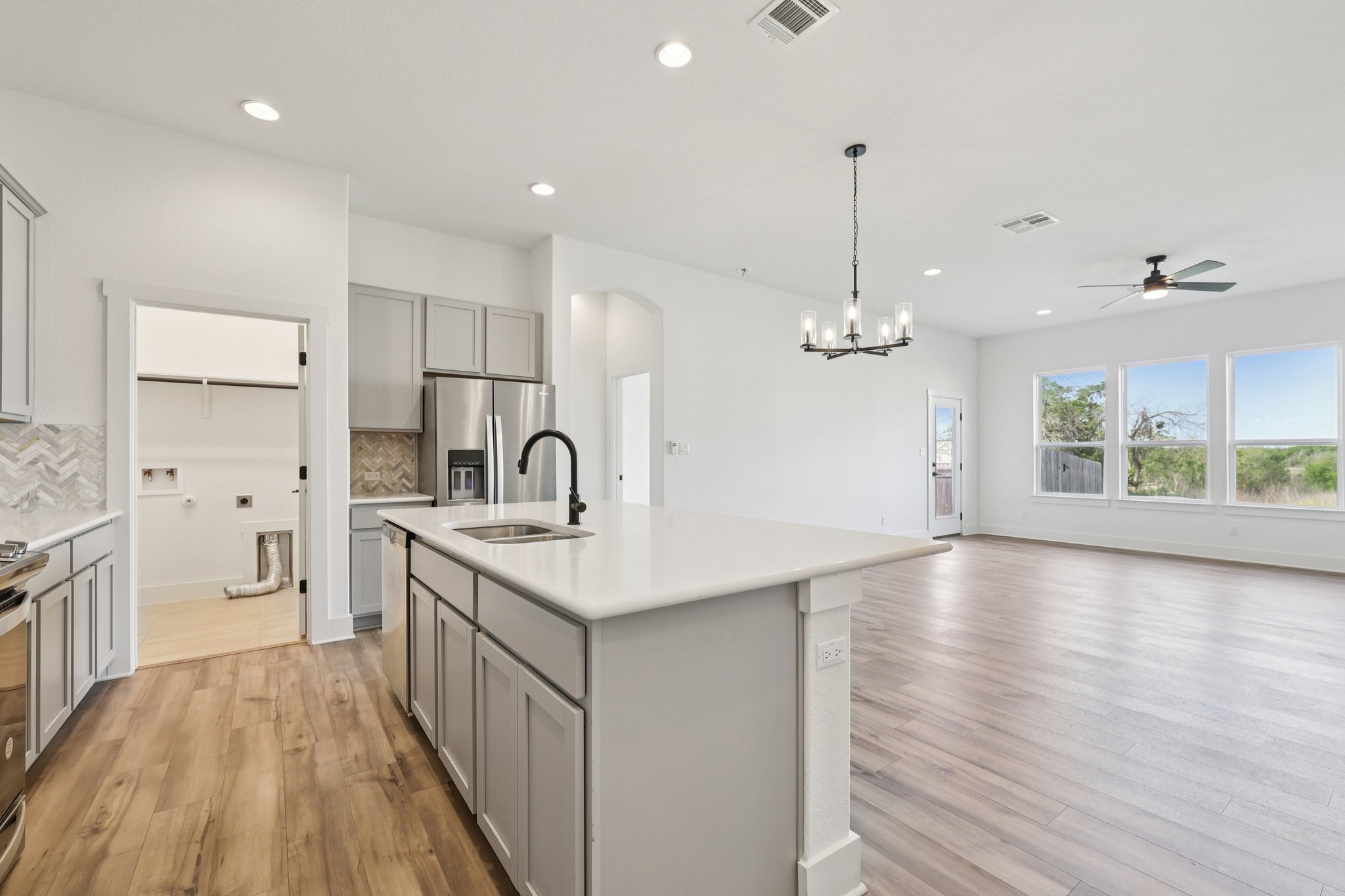 8760 Wellspring Loop Hutto, TX 78634 - Photo 37 of 37 Kitchen featuring gray cabinetry, stainless steel appliances, an island with sink, open floor plan, and tasteful backsplash