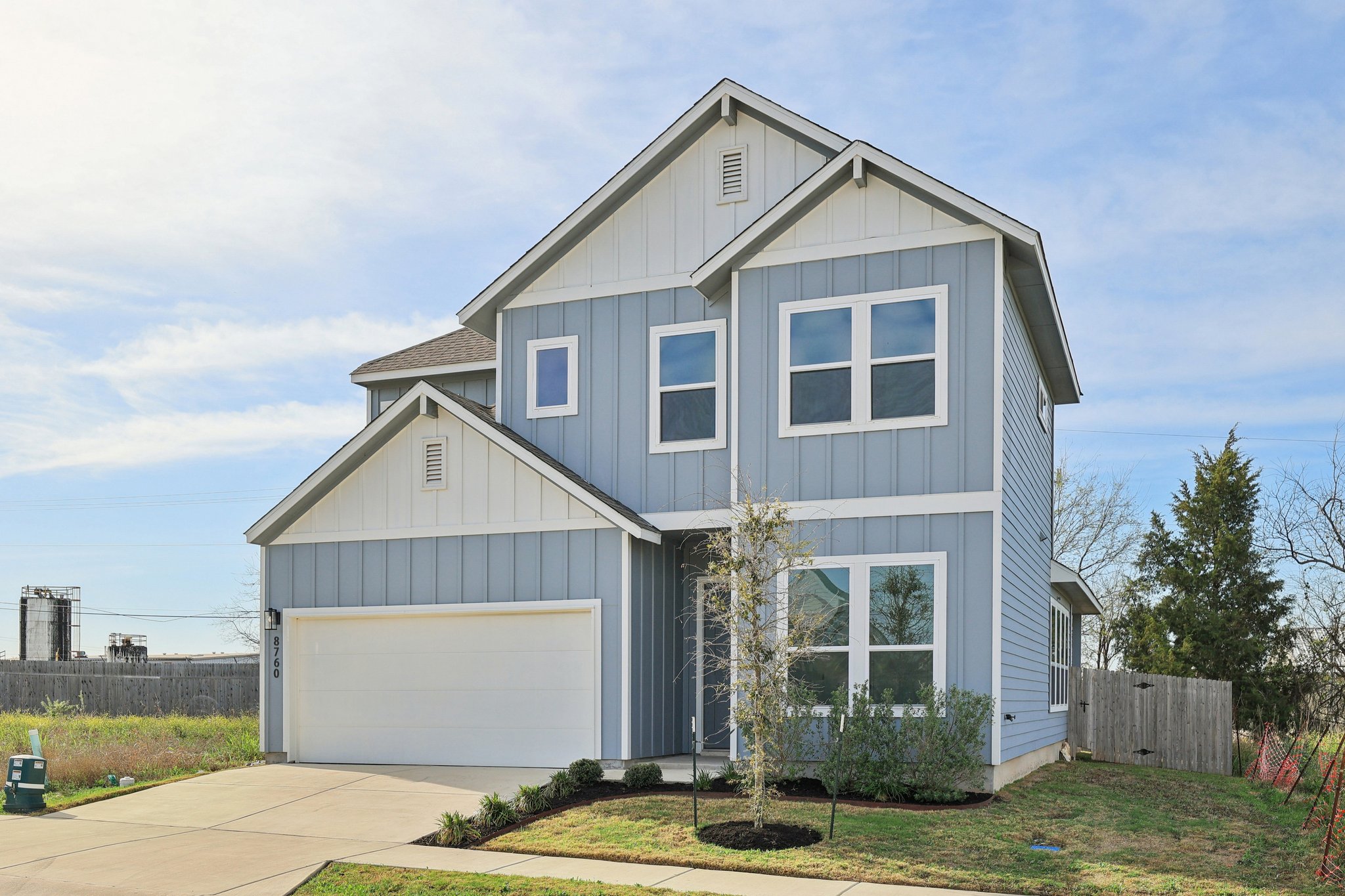 8760 Wellspring Loop Hutto, TX 78634 - Photo 6 of 37 View of front of property with board and batten siding, concrete driveway, an attached garage, and a gate