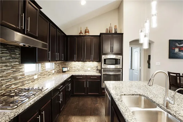 a kitchen with kitchen island granite countertop a sink stove and refrigerator
