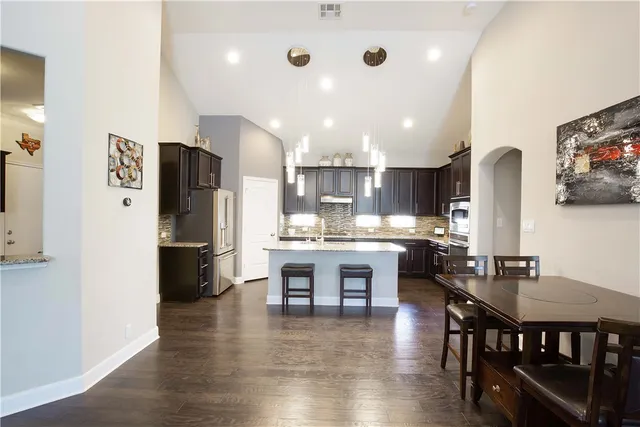 a kitchen with stainless steel appliances a dining table chairs and wooden floor