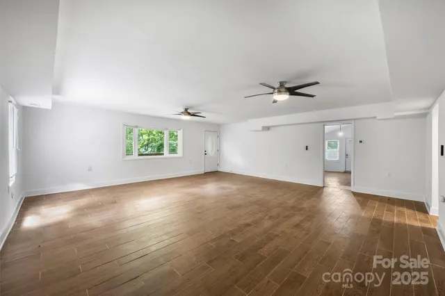 a view of an empty room with a window and wooden floor