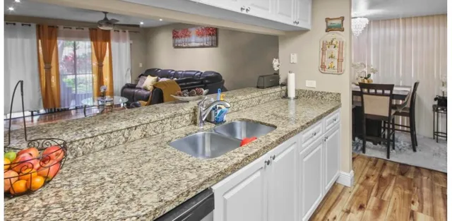 a kitchen with granite countertop a sink a stove and a wooden floor