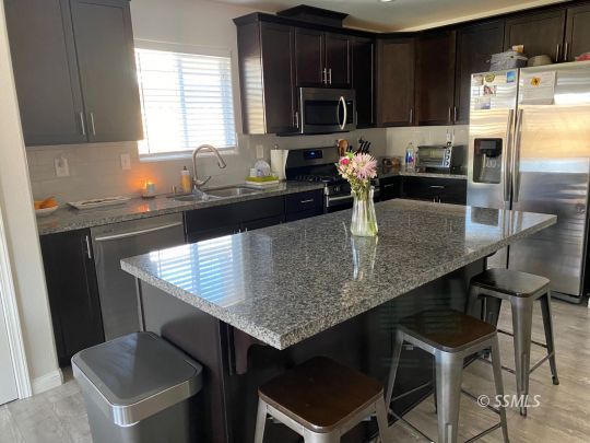 1113 Mayo Street Ridgecrest, CA 93555 - Photo 9 of 31 a kitchen with granite countertop kitchen island a table and chairs in it