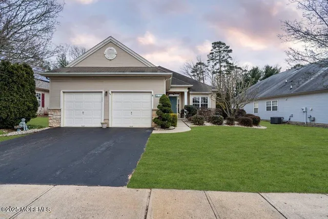 a front view of a house with a garden and trees
