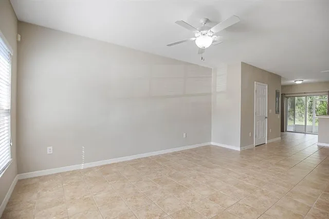 an empty room with a kitchen and a chandelier fan