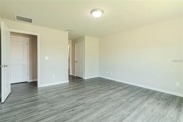 a view of an empty room with wooden floor and closet