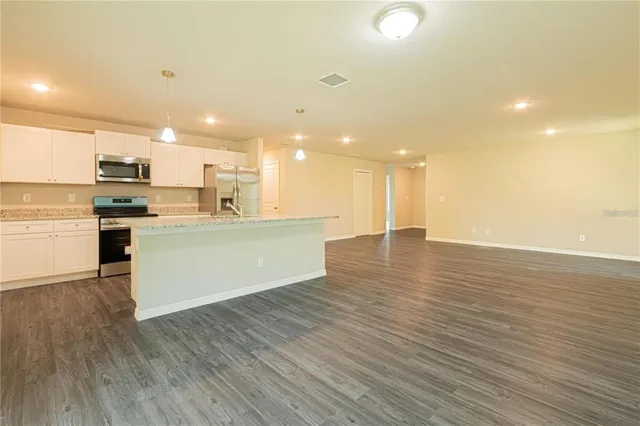 a view of kitchen with kitchen island wooden floors and stainless steel appliances