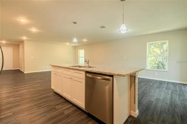 a kitchen with stainless steel appliances granite countertop a sink a stove a refrigerator and island with wooden floor