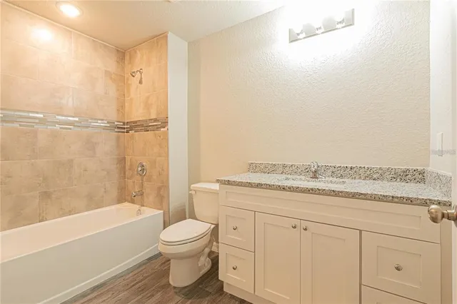 a bathroom with a granite countertop sink a toilet and bathtub