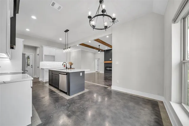 a large white kitchen with a large window a counter space and stainless steel appliances