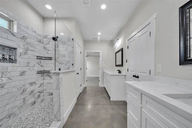 a large white bathroom with a double vanity sink a mirror and a shower
