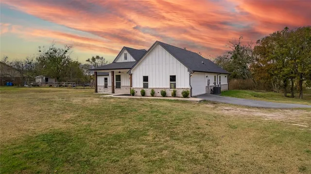 a view of a house next to a big yard with large trees