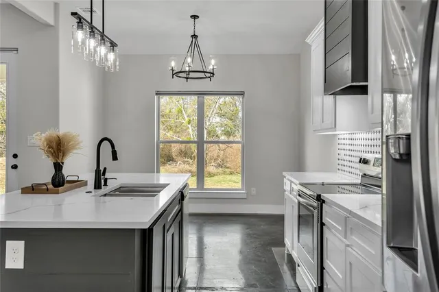 a kitchen with stainless steel appliances granite countertop a sink a stove and a refrigerator