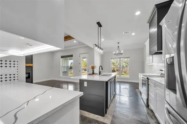 a kitchen with stainless steel appliances kitchen island granite countertop a sink a stove and a refrigerator