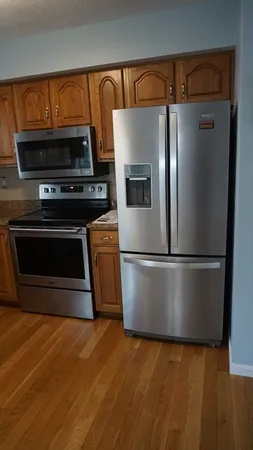 a view of a kitchen with wooden floor and a refrigerator