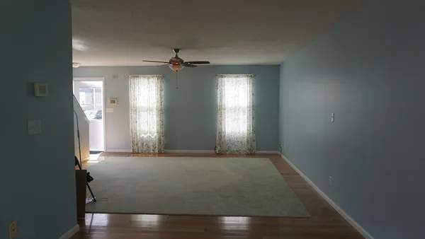an empty room with wooden floor and windows