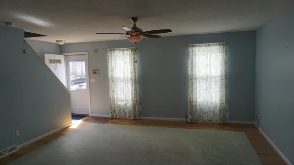 an empty room with windows and fan