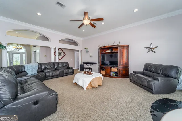 a living room with furniture kitchen view and a chandelier