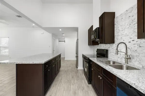 a large kitchen with stainless steel appliances granite countertop a refrigerator and a sink