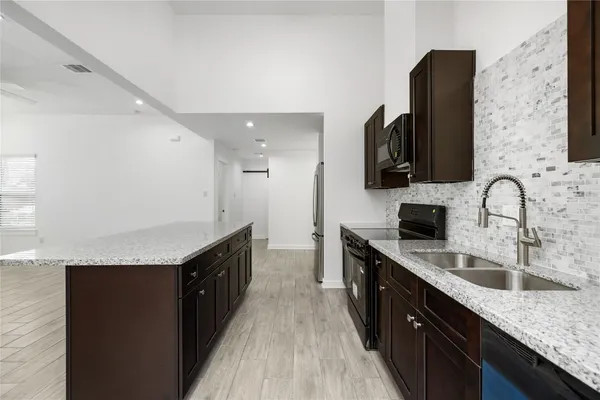 a large kitchen with stainless steel appliances granite countertop a refrigerator and a sink
