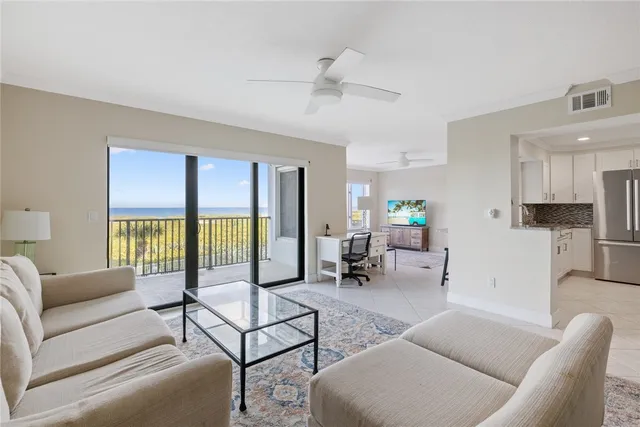 a living room with furniture kitchen view and a large window