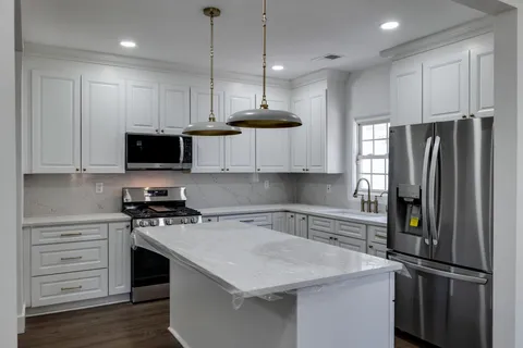 a kitchen with stainless steel appliances a stove a sink a refrigerator a microwave and cabinets