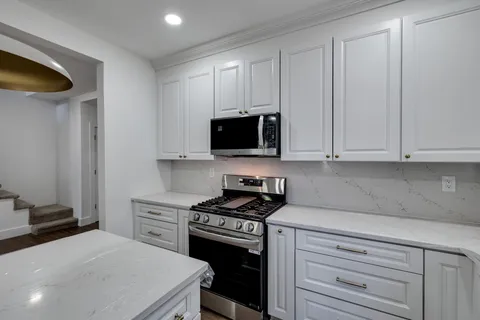 a kitchen with granite countertop white cabinets and stainless steel appliances