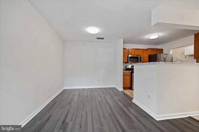 a view of a kitchen with a fridge and wooden floor