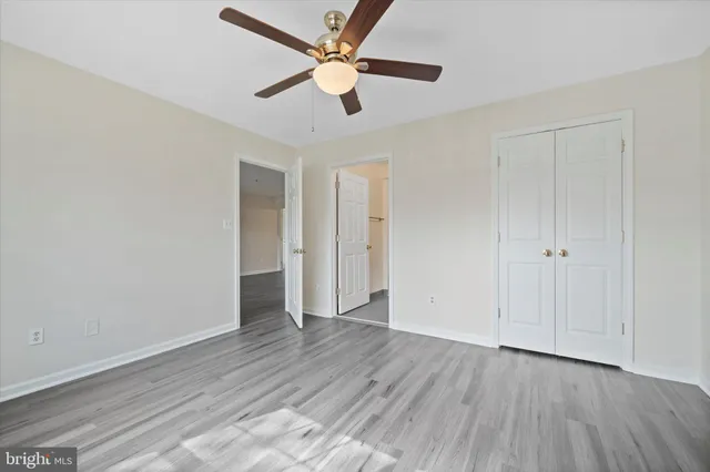 an empty room with wooden floor ceiling fan and windows